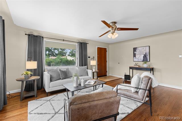 Staged living room with gray sofa, armchairs, geometric rug, and a large curtained window.