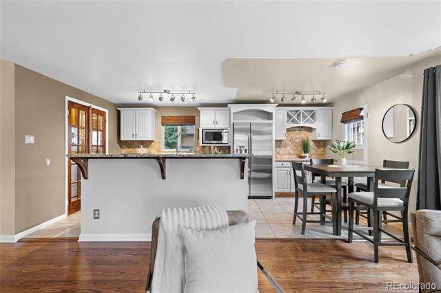 Open-plan kitchen and dining area with white cabinets, stainless appliances, and a dark countertop peninsula.