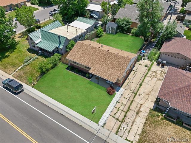 Aerial view of a brick ranch home with a broad front lawn and fenced backyard.