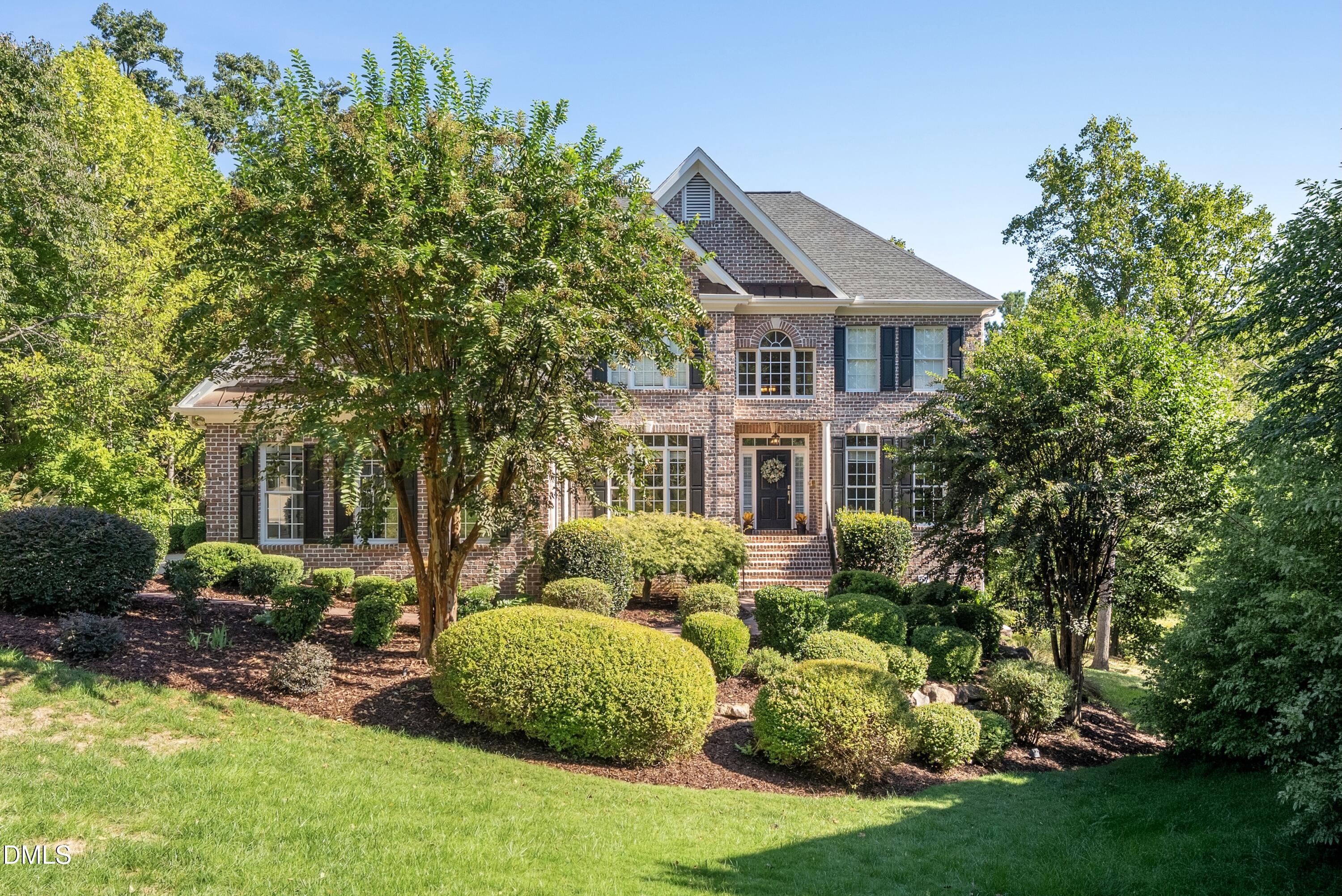 Two-story brick house with an arched window and landscaped front yard.