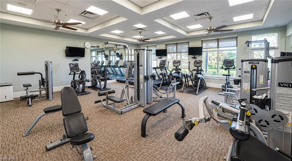 Fitness center with weight machines and cardio equipment beside large windows.