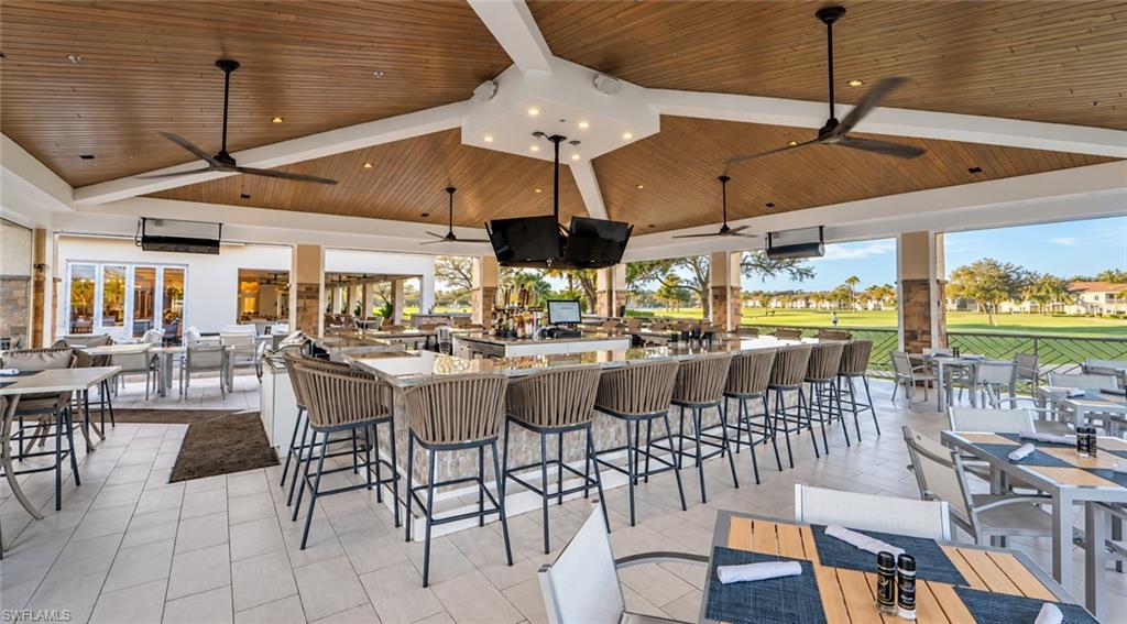 Open-air clubhouse bar with a vaulted wood ceiling and views of the golf course.