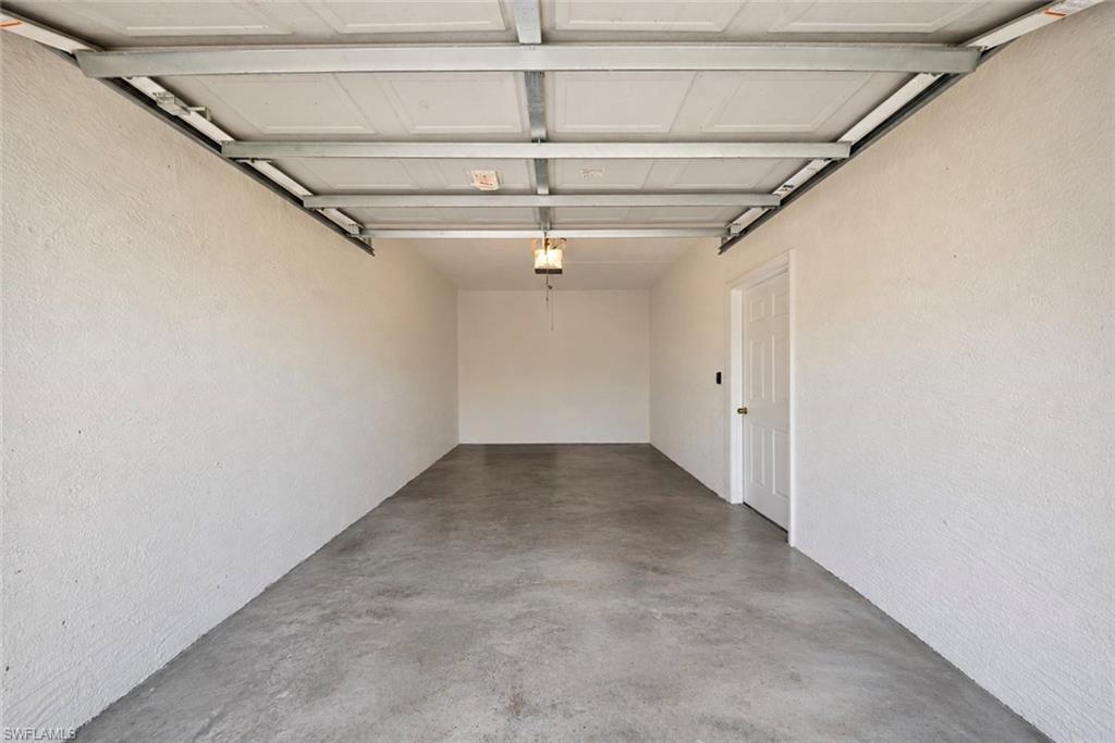 Empty garage with a concrete floor, white walls, and an overhead door.