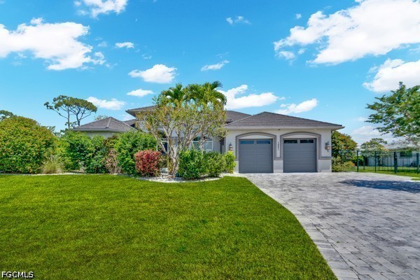 Single-story home with a two-car garage, paved driveway, and landscaped front lawn.