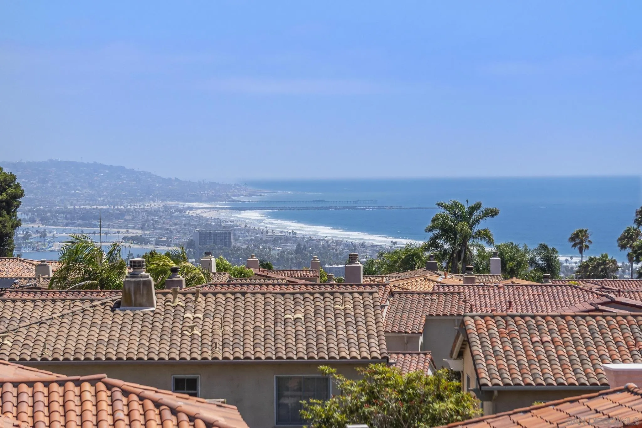 Coastal homes with terracotta roofs overlook the La Jolla shoreline and Pacific Ocean.