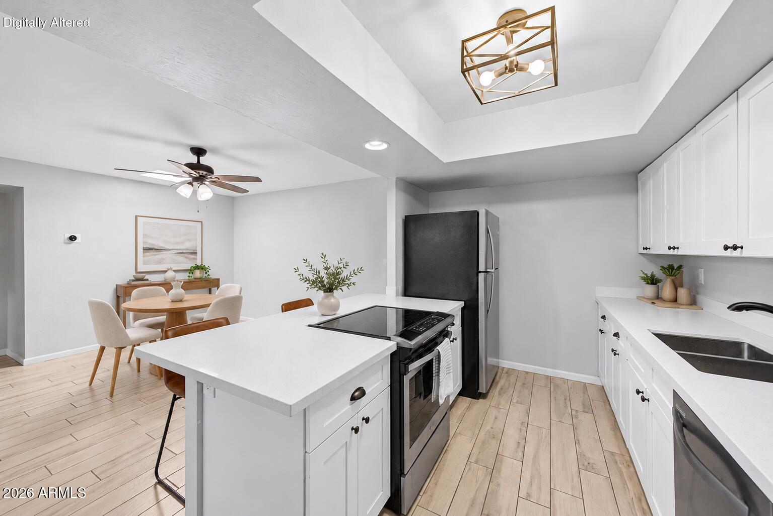 Open-plan kitchen with a white island and cooktop, stainless steel appliances, and an adjoining dining area.