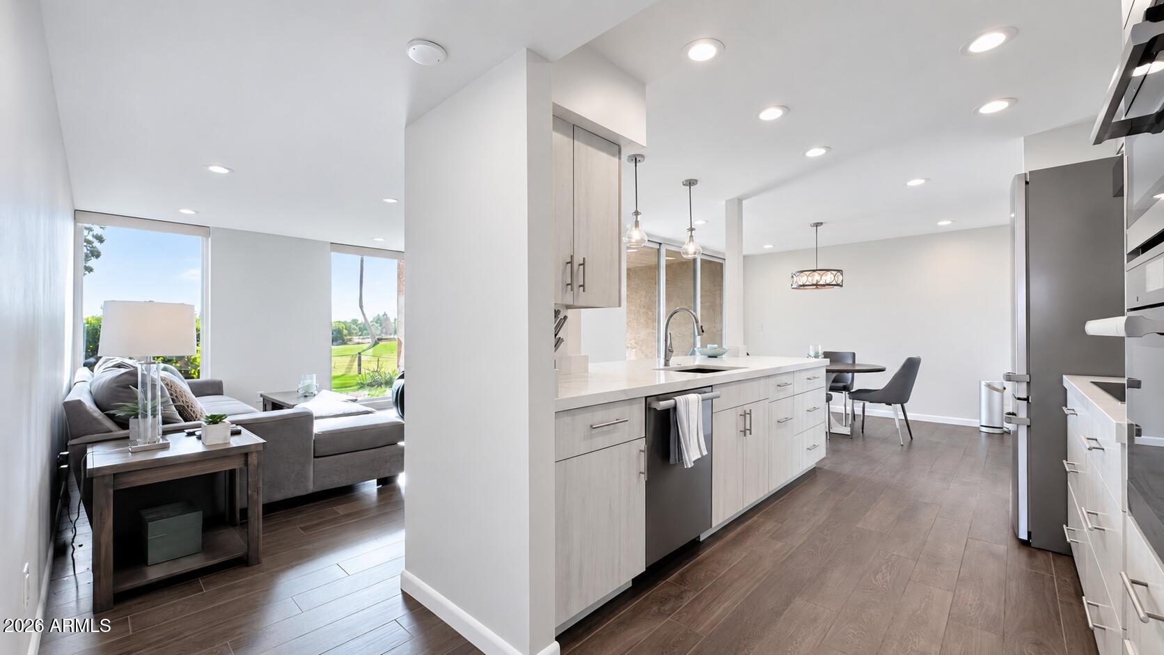 Open-plan kitchen and living area with a large island and windows overlooking a green lawn.