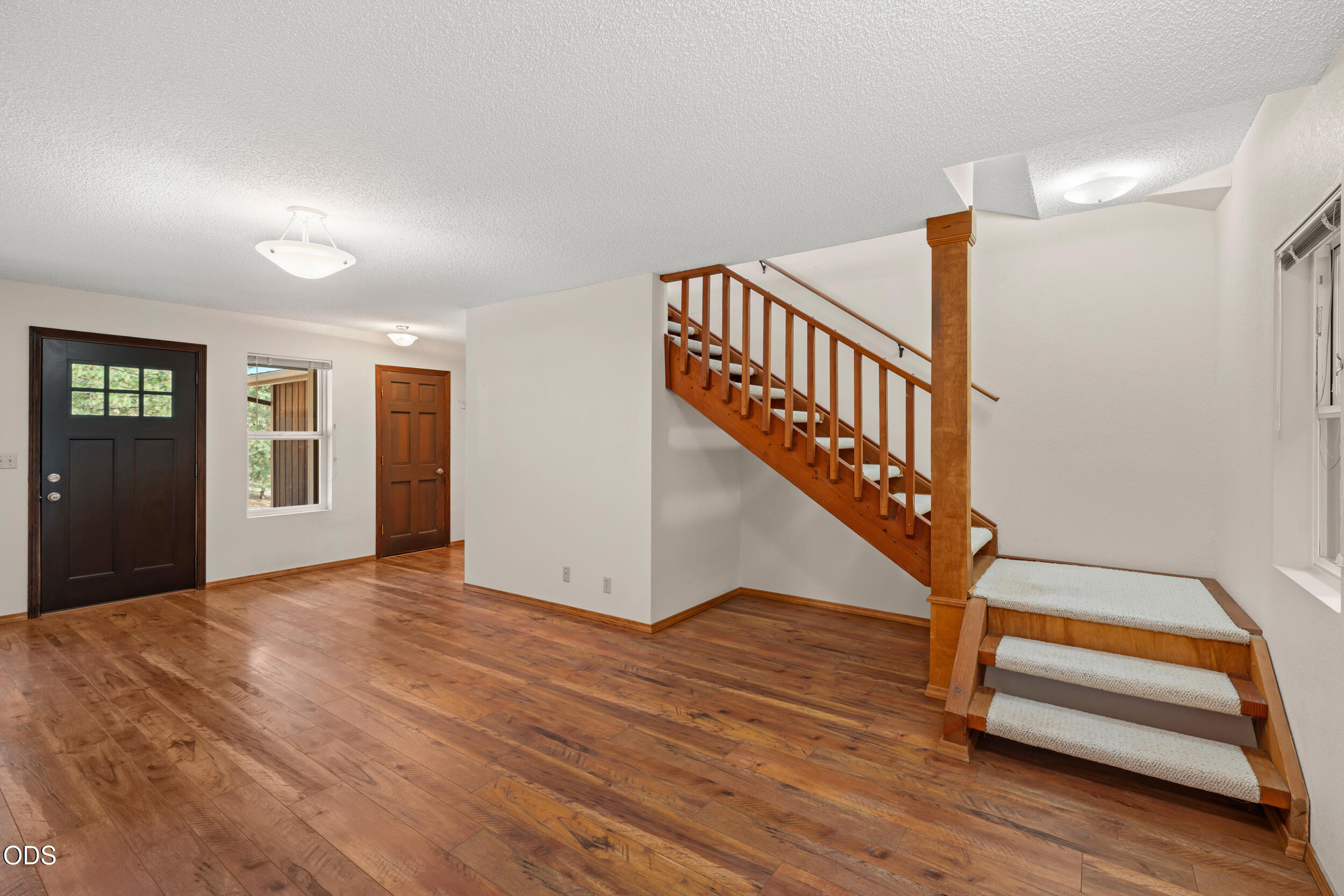 Entry foyer with hardwood floors and a wooden staircase with carpet runners.