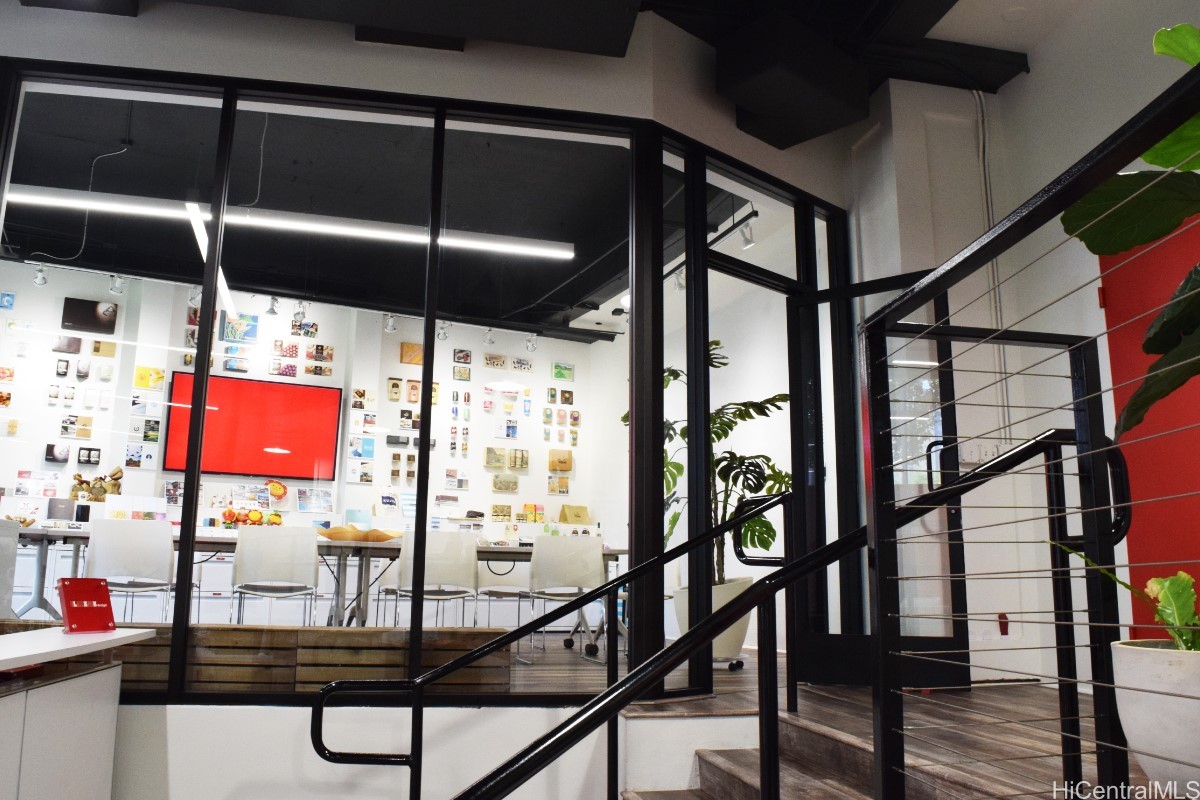 Furnished interior with glass partitions, display wall, and black metal staircase.