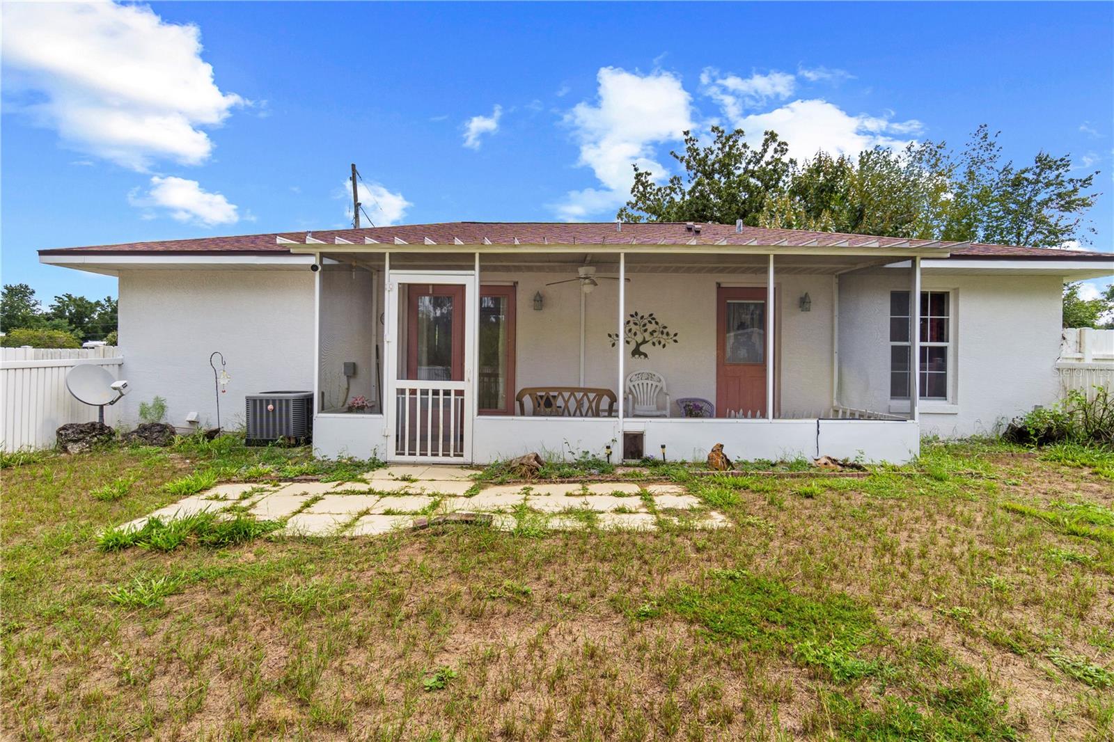 Single-story home with a covered screened porch and patchy grassy yard.