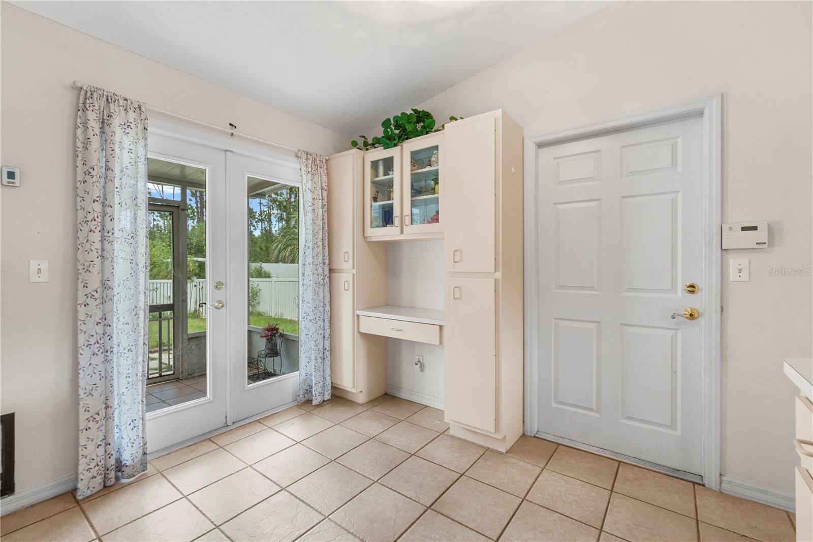 Tiled entryway with built-in cabinets, a paneled front door, and glass doors to a covered patio.