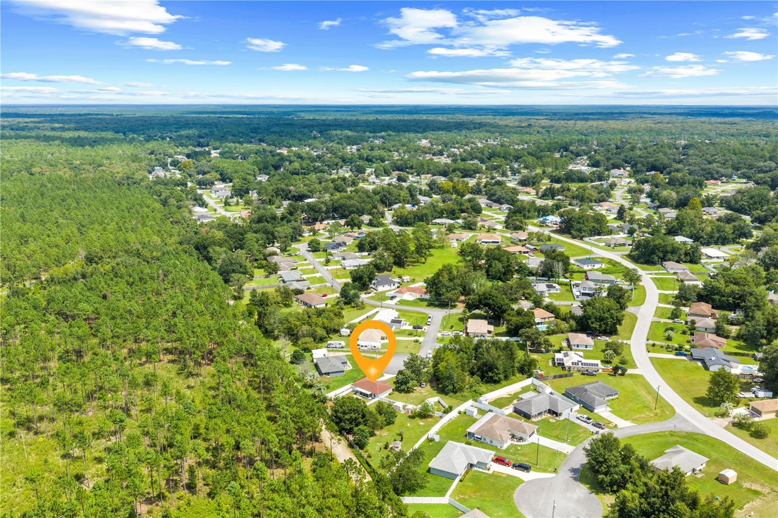 Aerial view of the marked home amid a leafy Ocala neighborhood and wooded area.