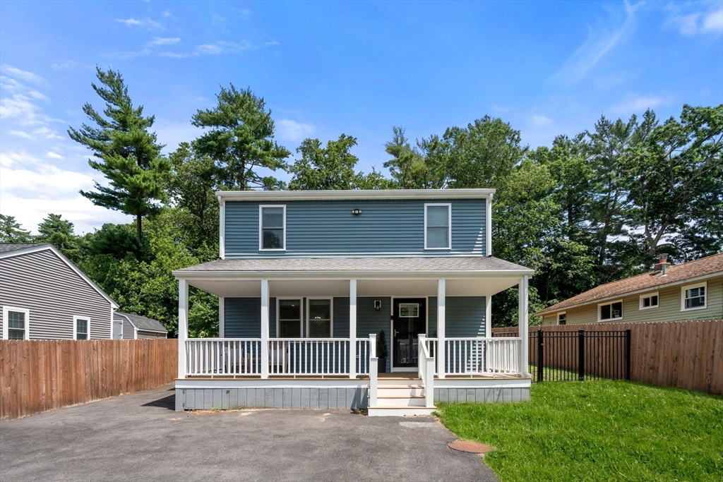 Blue two-story home with a white-railed covered porch and asphalt driveway.