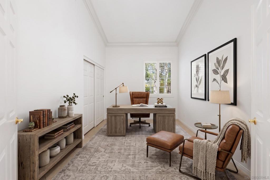 Home office with a wood desk, shuttered windows, and a leather armchair and ottoman.