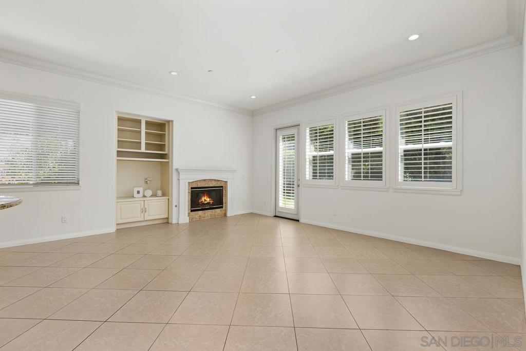 Unfurnished living room with a tile floor, built-in fireplace and shelving, and shuttered windows.