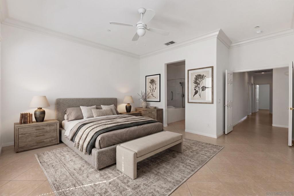 Staged bedroom with an upholstered bed, foot-of-bed bench, ceiling fan, and doorway to a tiled shower.
