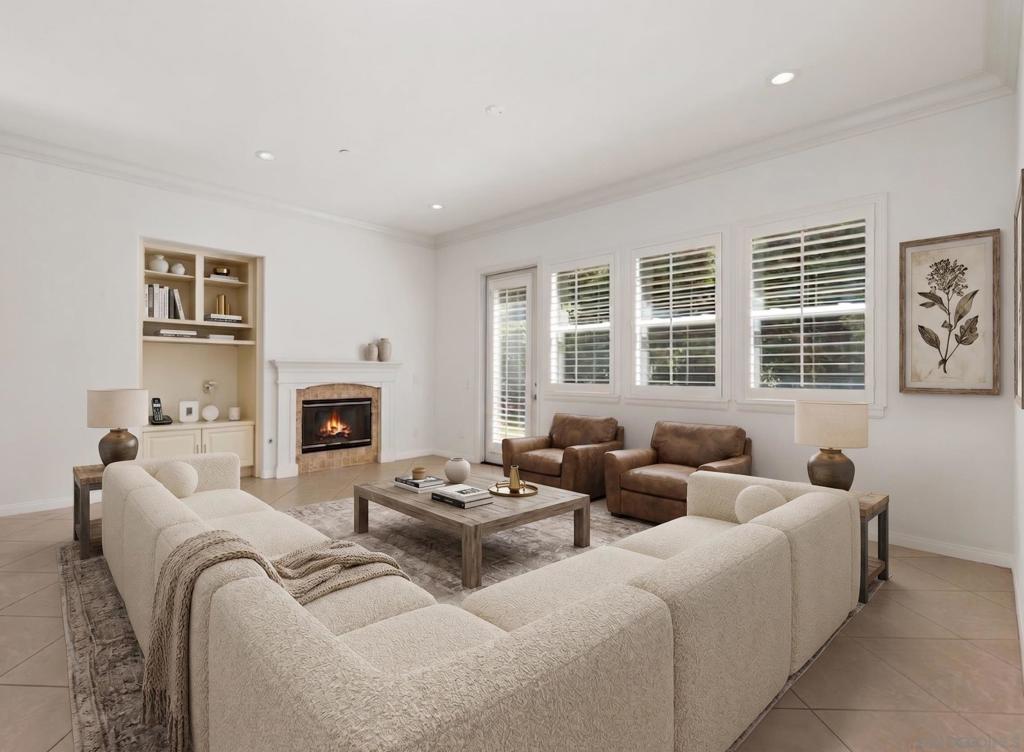 Staged living room with a white sectional, brown leather chairs, and a fireplace.