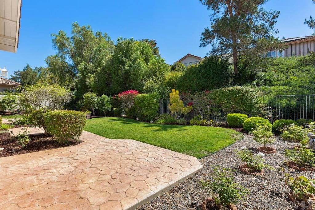 Backyard with a stamped-stone patio, green lawn, gravel beds, and mature trees.