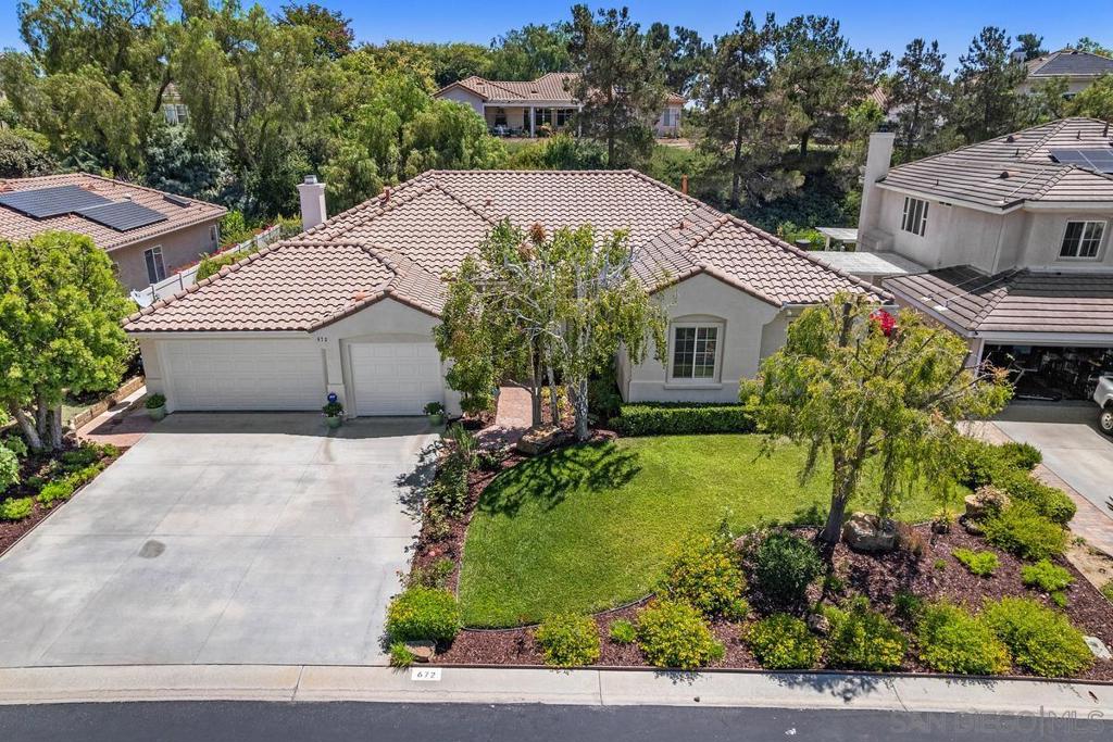 Aerial view of a single-story home with a tile roof, two-car garage, and landscaped front yard.