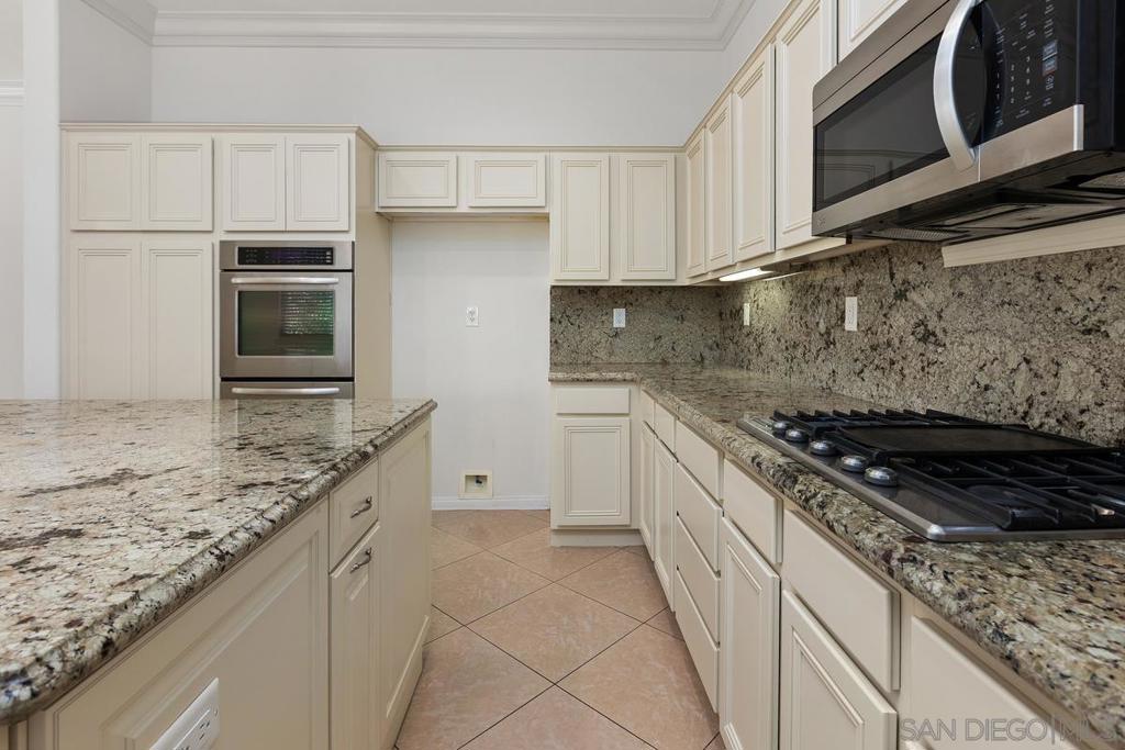 Kitchen with cream cabinets, granite counters, a central island, built-in oven, and gas cooktop.