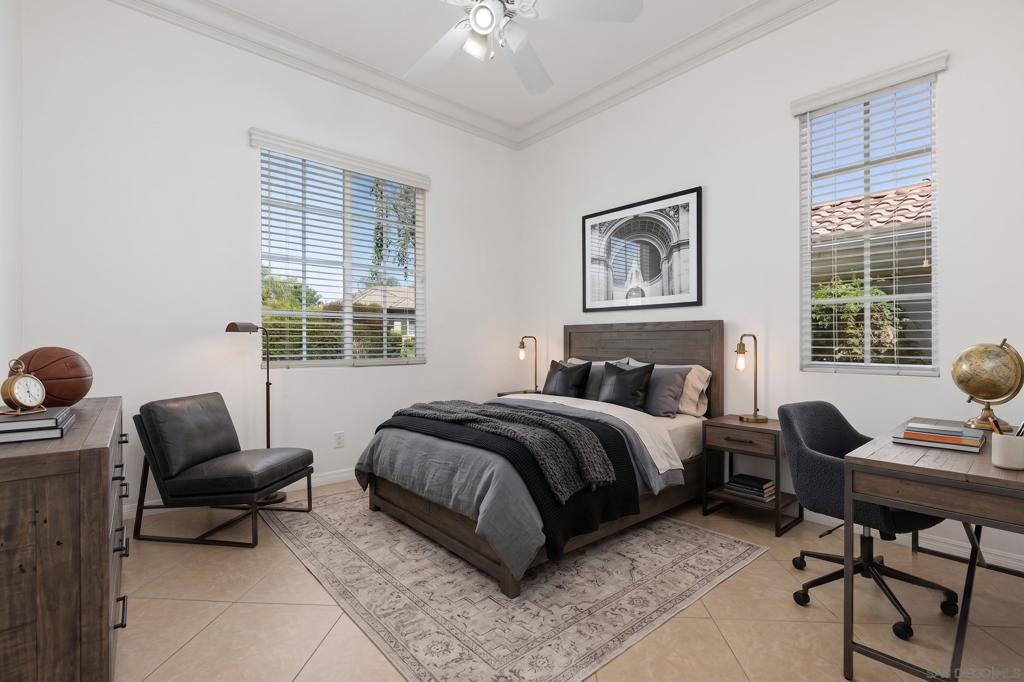 Bedroom with gray bedding, a patterned rug, and two bright windows.