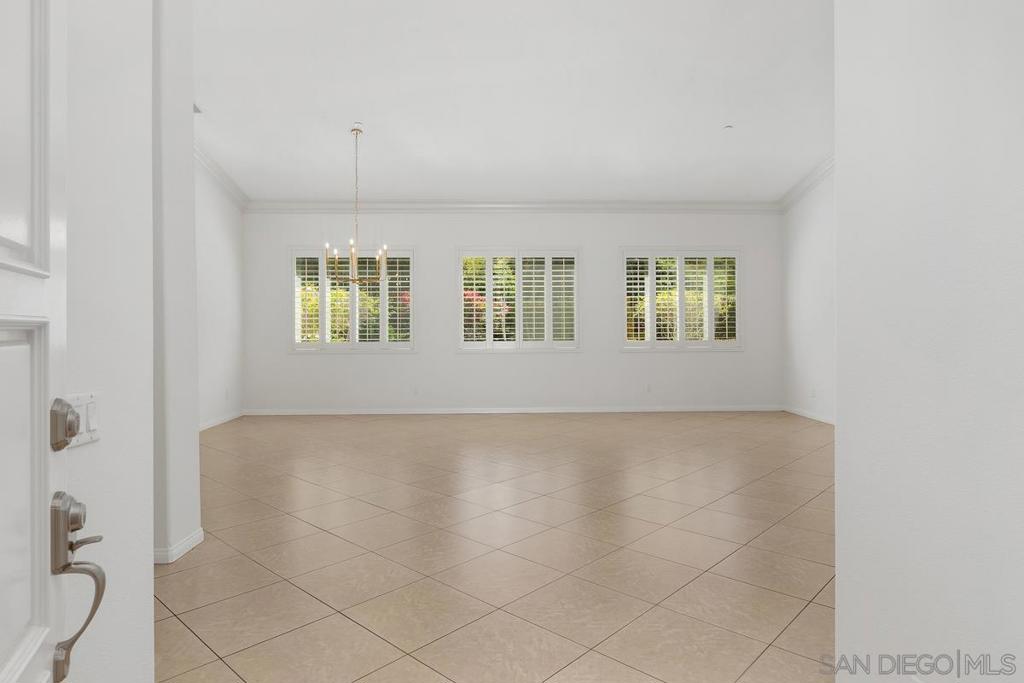 Empty tiled room with three shuttered windows and a hanging light fixture.