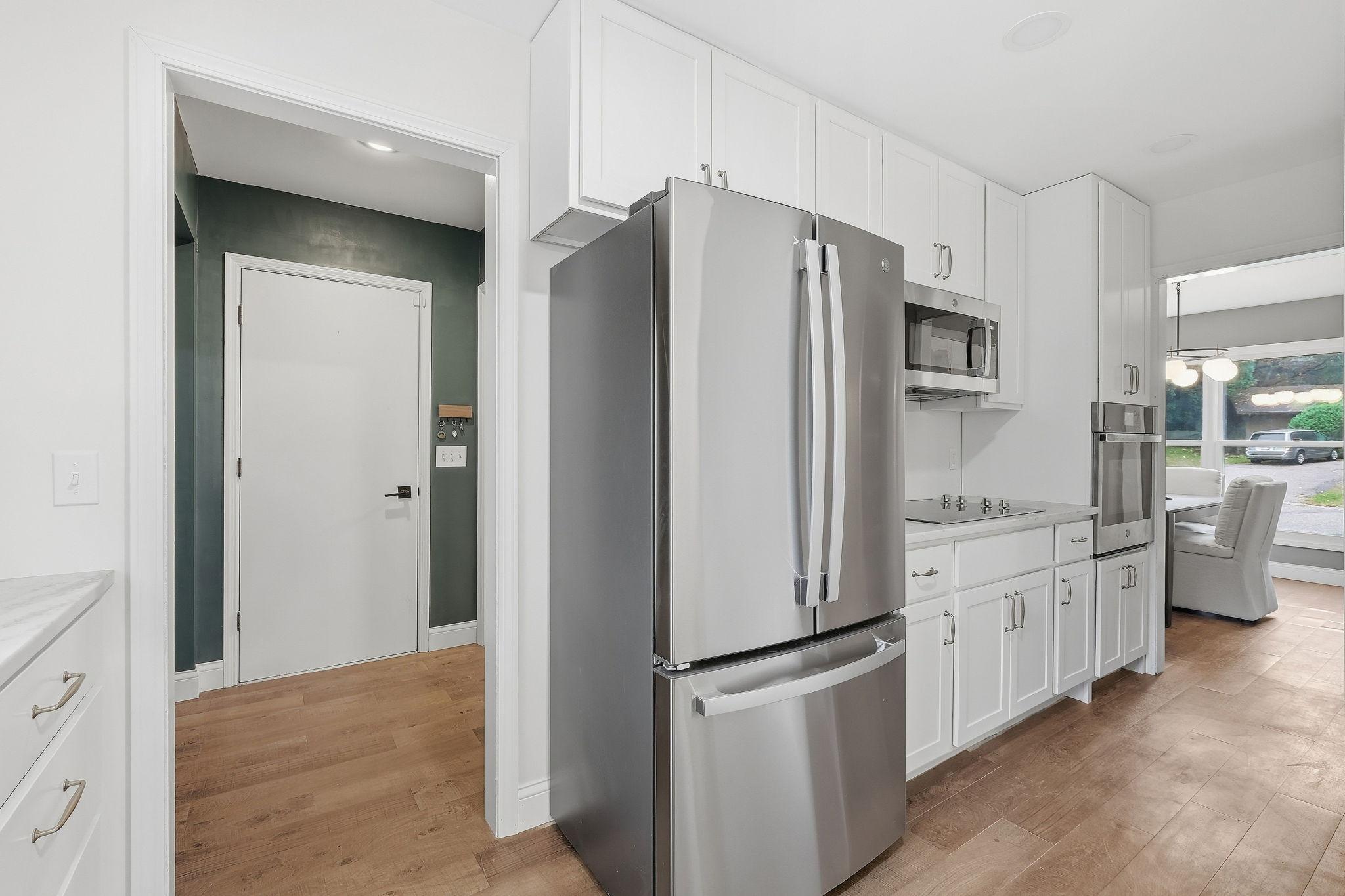 Kitchen with white cabinets, stainless steel appliances, wood flooring, and an adjoining dining area.