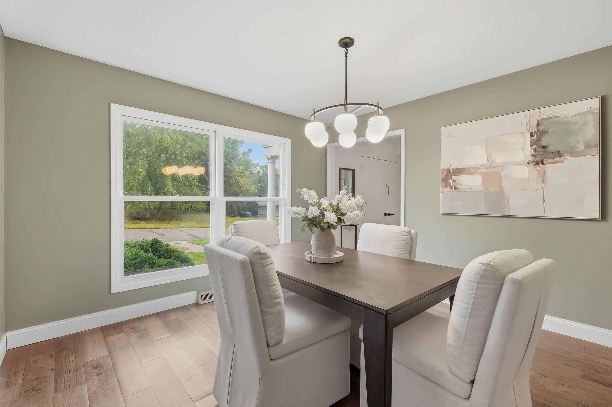 Dining room with a dark table, upholstered chairs, large windows, and a modern globe chandelier.