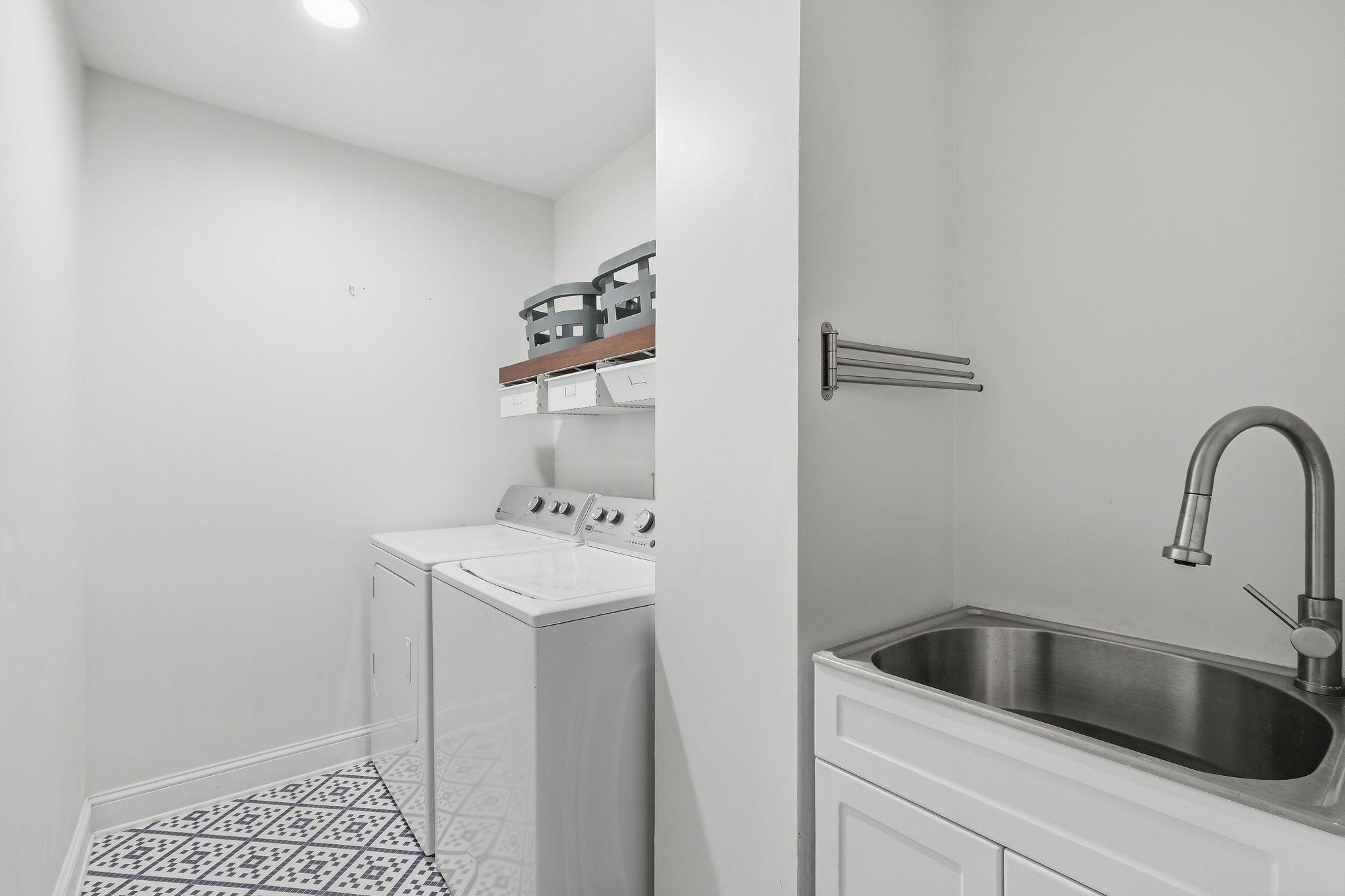 Laundry room with washer and dryer, a stainless utility sink, and geometric patterned floor tile.