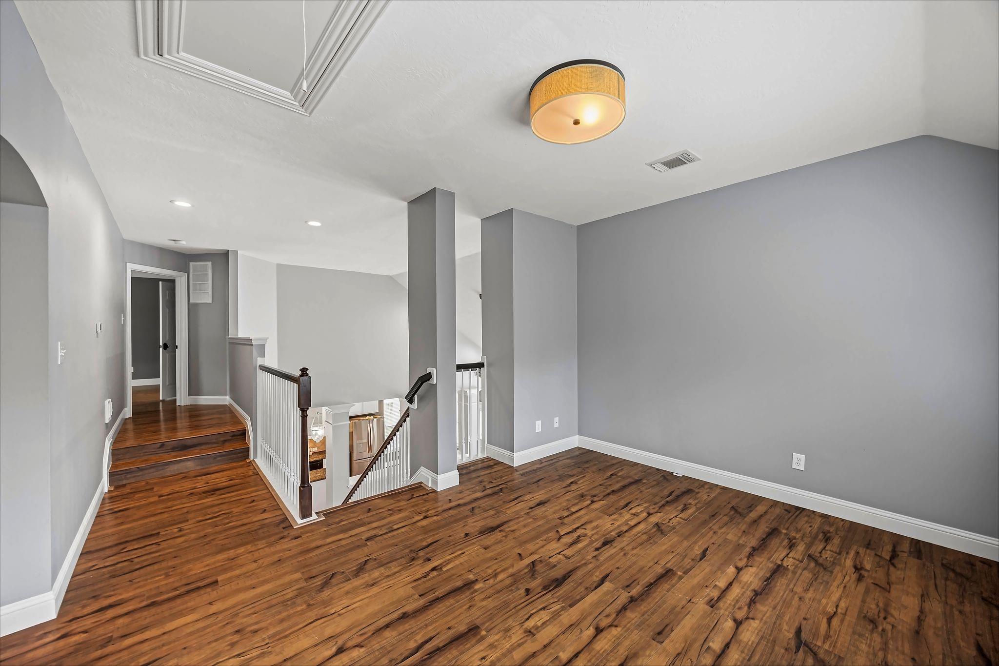 Vacant upstairs landing with dark hardwood floors and an open stairwell.