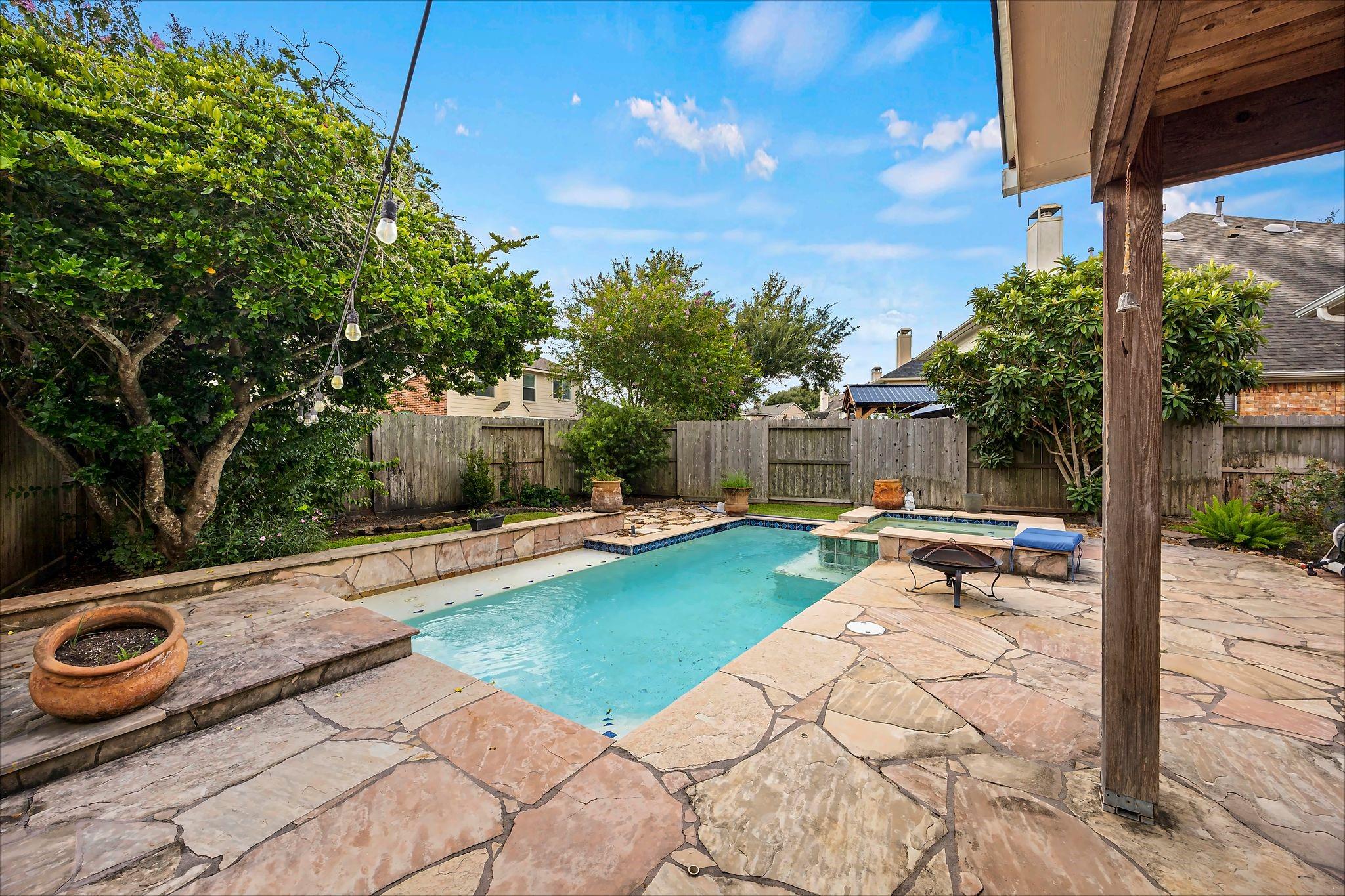 Backyard pool and spa with a flagstone patio, mature trees, and covered timber patio.