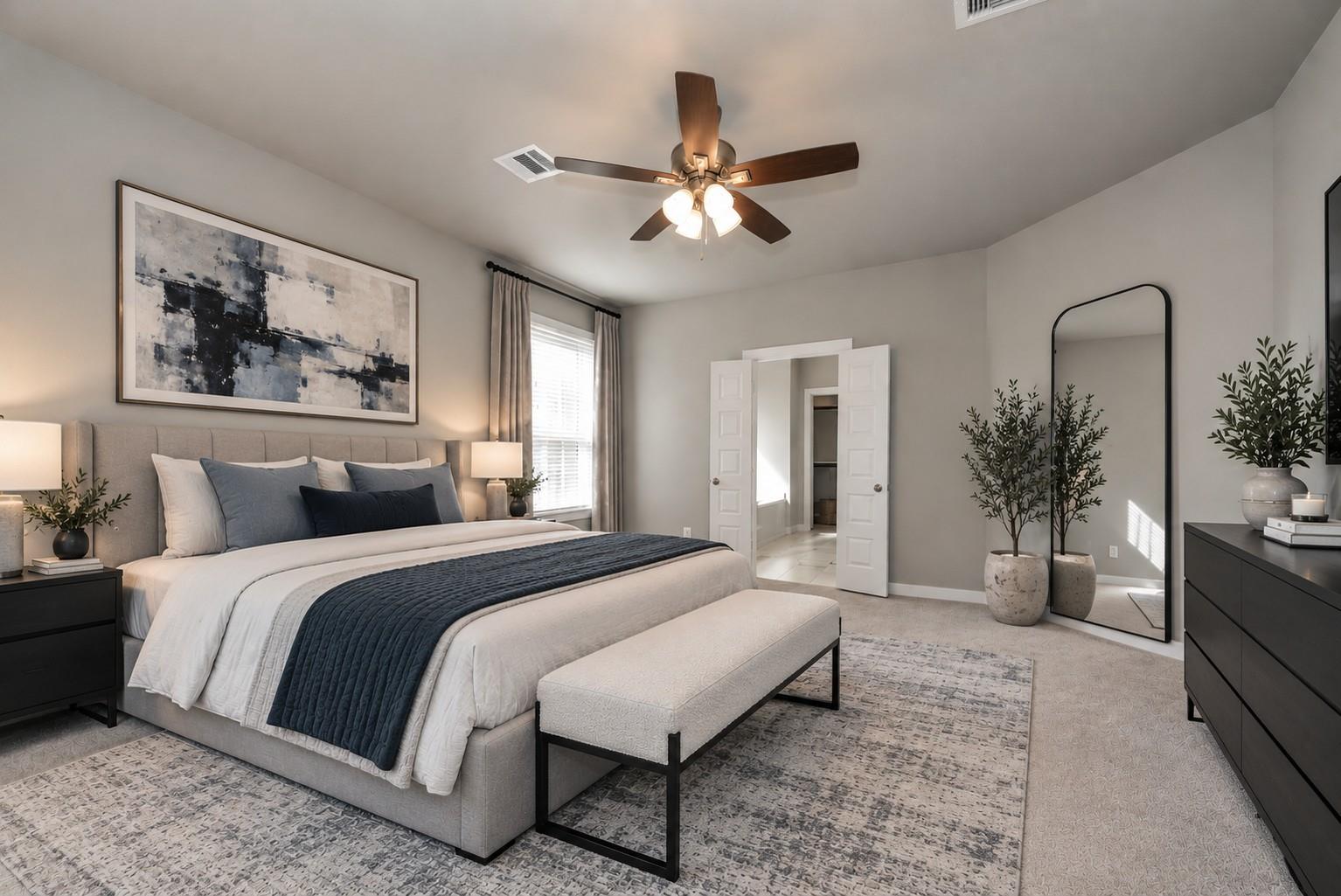 Staged bedroom with a large upholstered bed, navy bedding, abstract wall art, and a full-length mirror.
