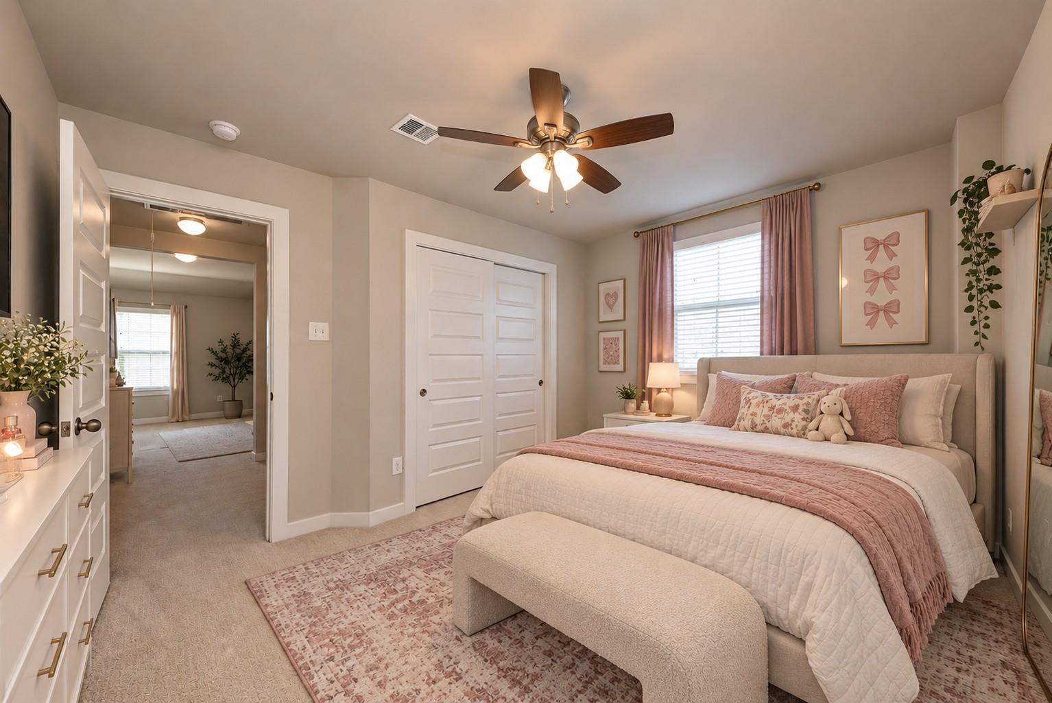 Bedroom with blush pink bedding, a cushioned bench, and white double closet doors.