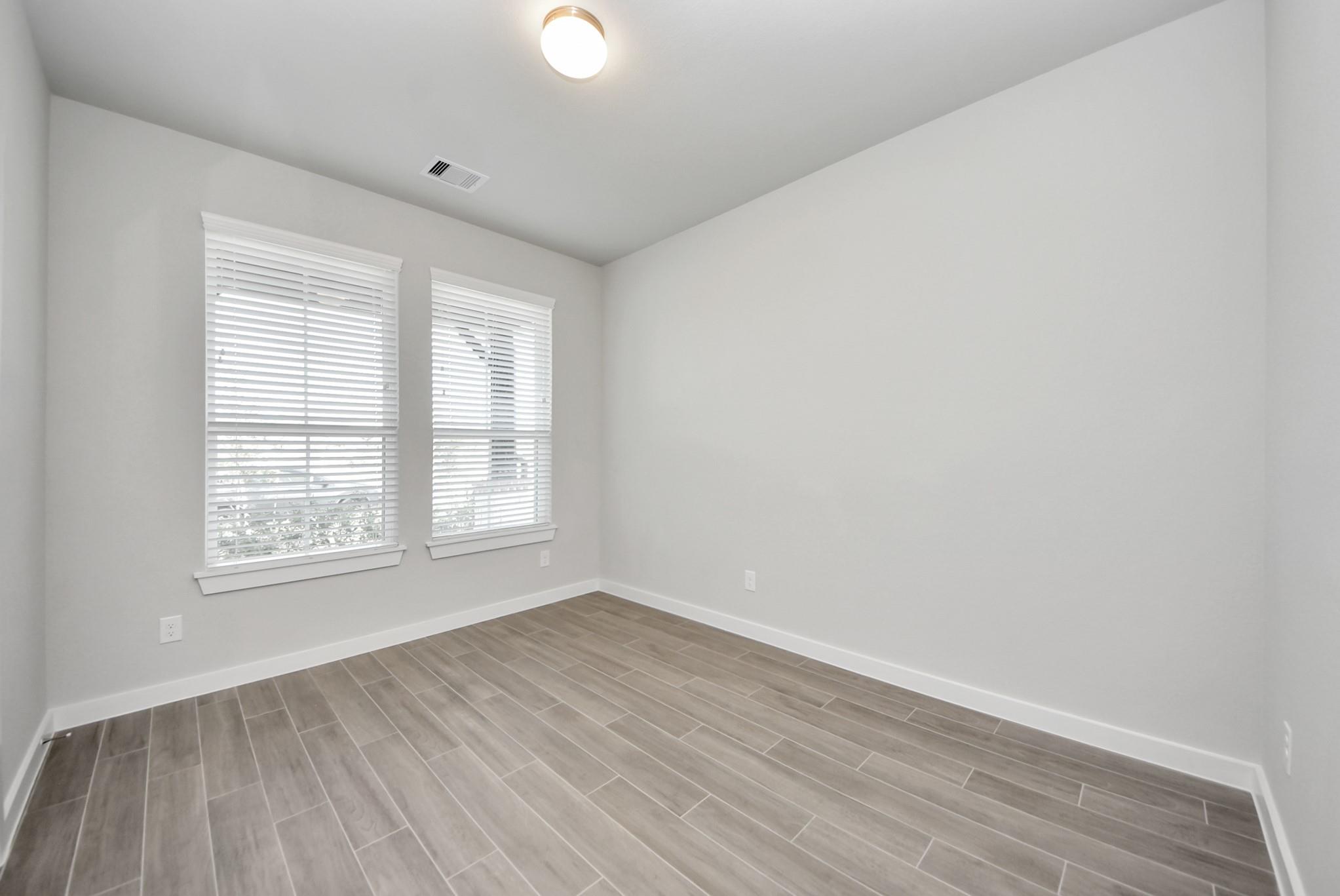 Empty room with gray tile flooring and two windows with white blinds.
