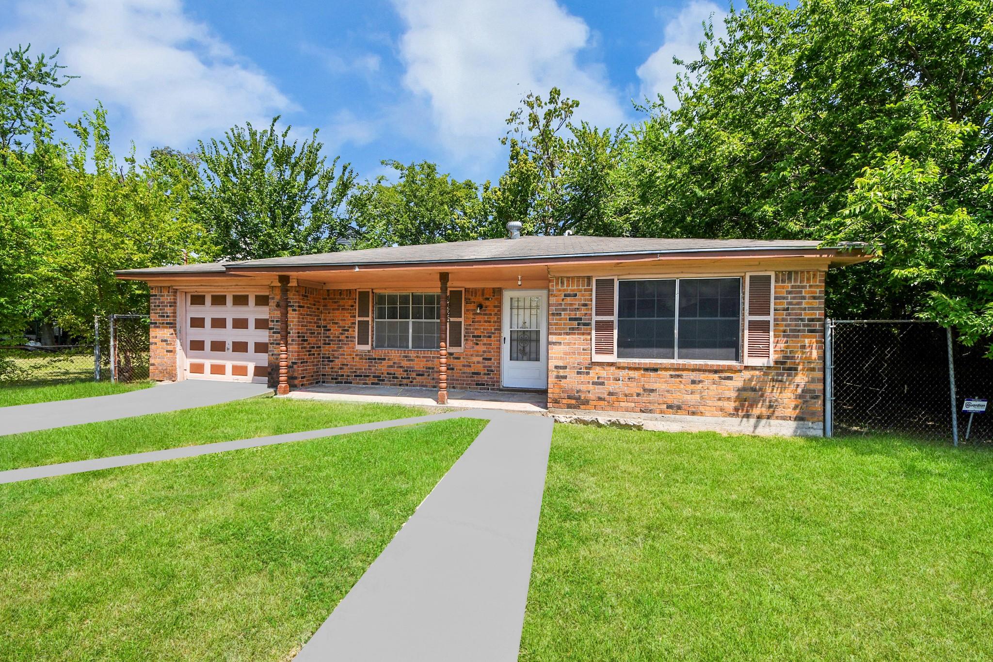 Single-story brick house with an attached garage, covered porch, and broad green lawn.