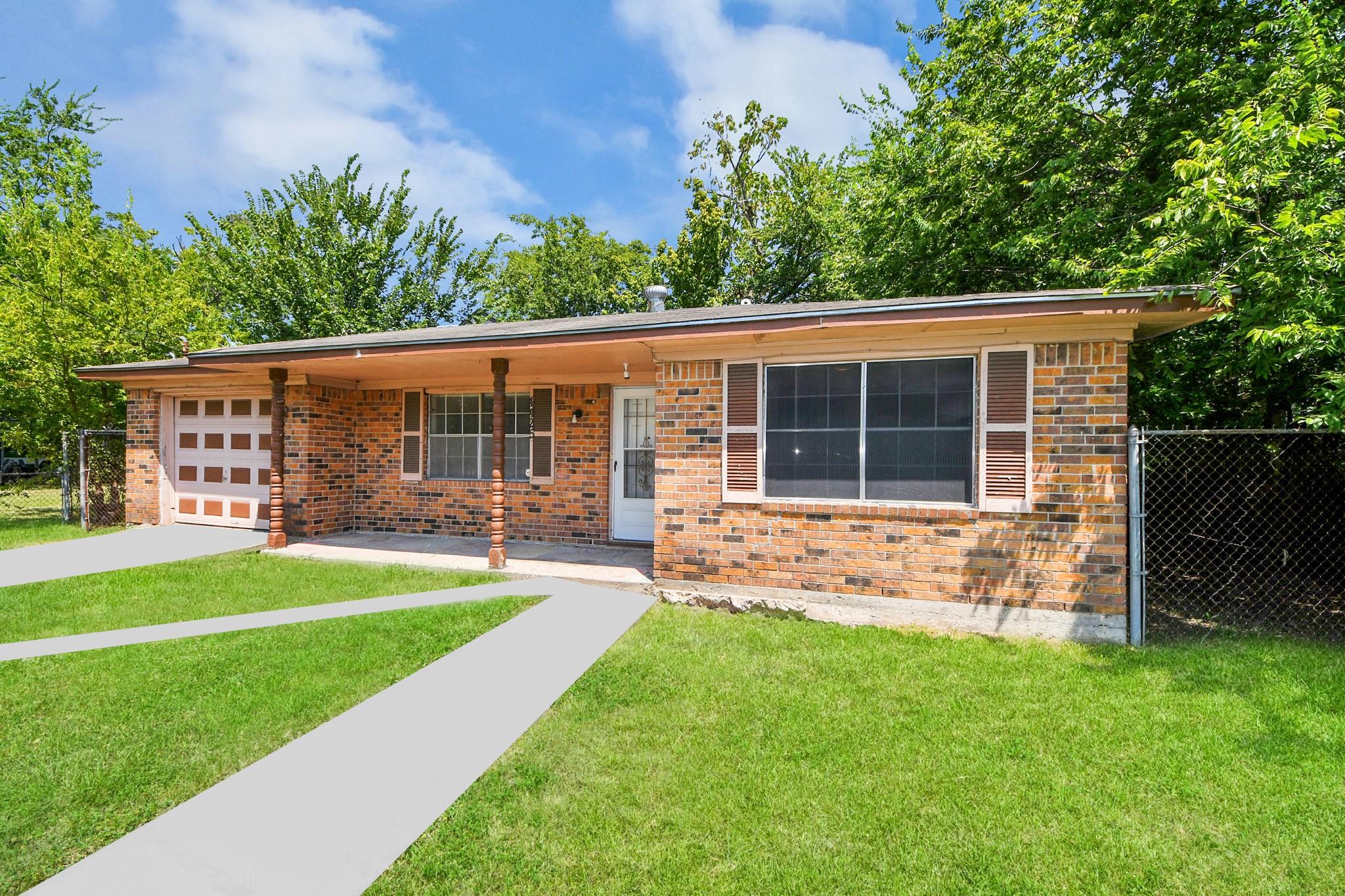Single-story brick house with a covered porch, attached garage, and concrete walkway across the lawn.