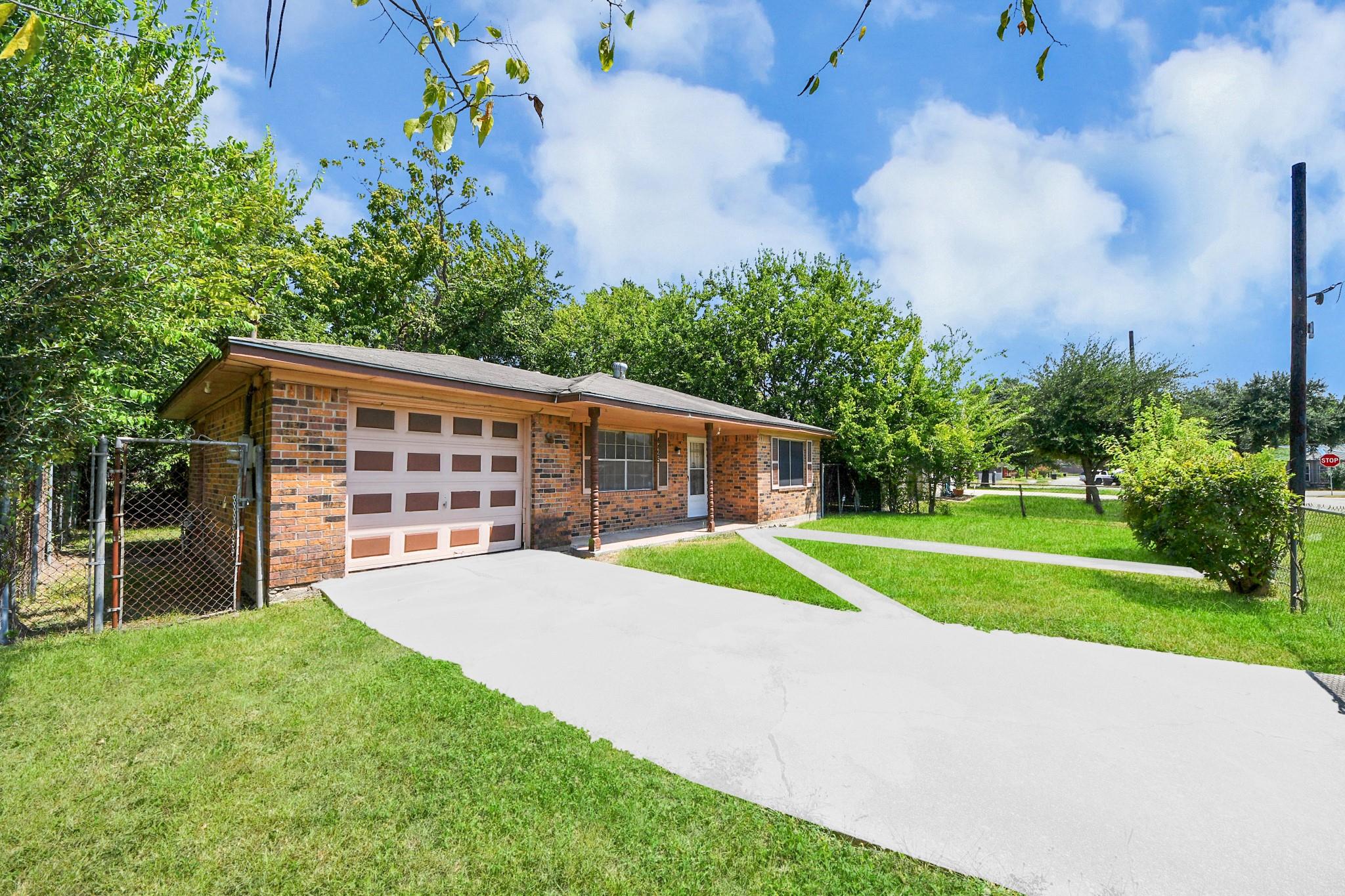 Single-story brick house with an attached garage, wide driveway, and green front lawn.