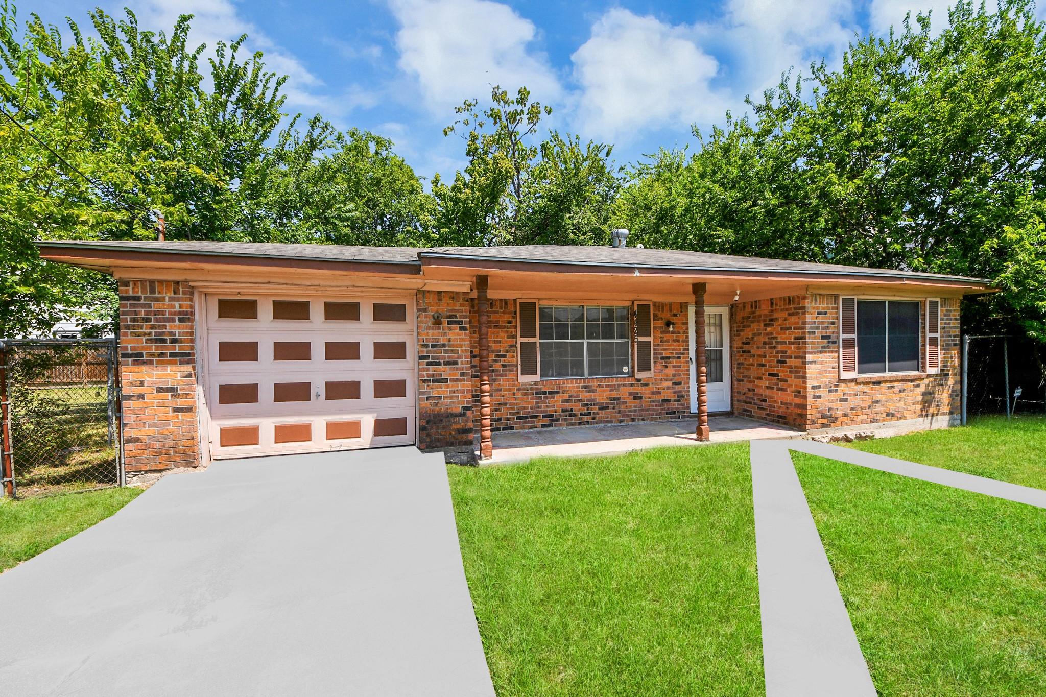 Single-story brick house with an attached garage, covered porch, and leafy front yard.