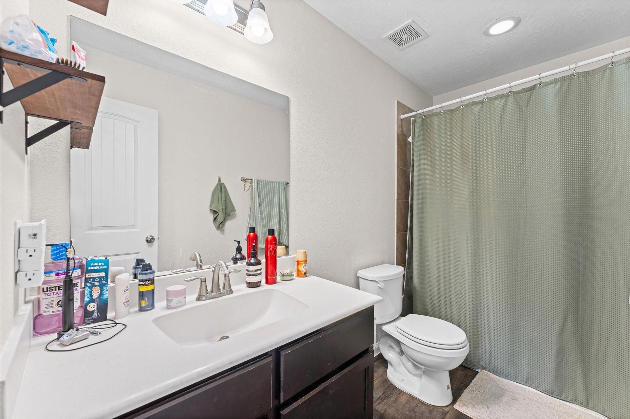 Bathroom with a white vanity, dark cabinets, and green shower curtain.