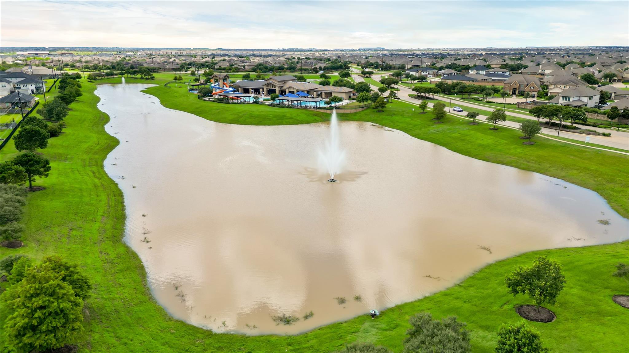 Aerial view of a neighborhood lake with a fountain and community pool