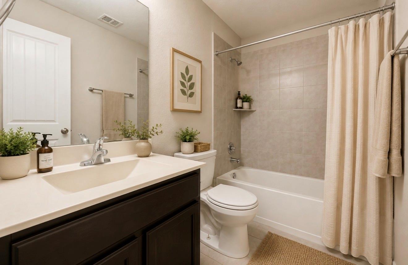 Bathroom with dark wood vanity, white sink, toilet, and beige-tiled tub and shower.