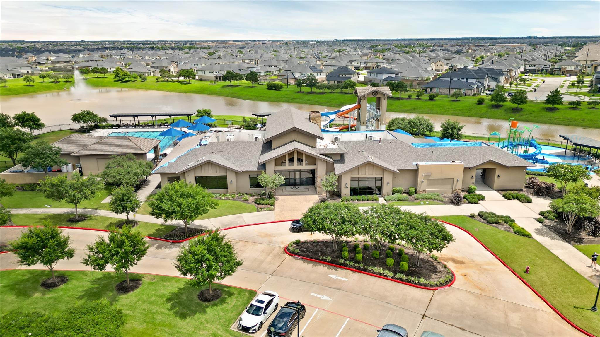Aerial view of a neighborhood recreation center with pools, water slides, and a pond.
