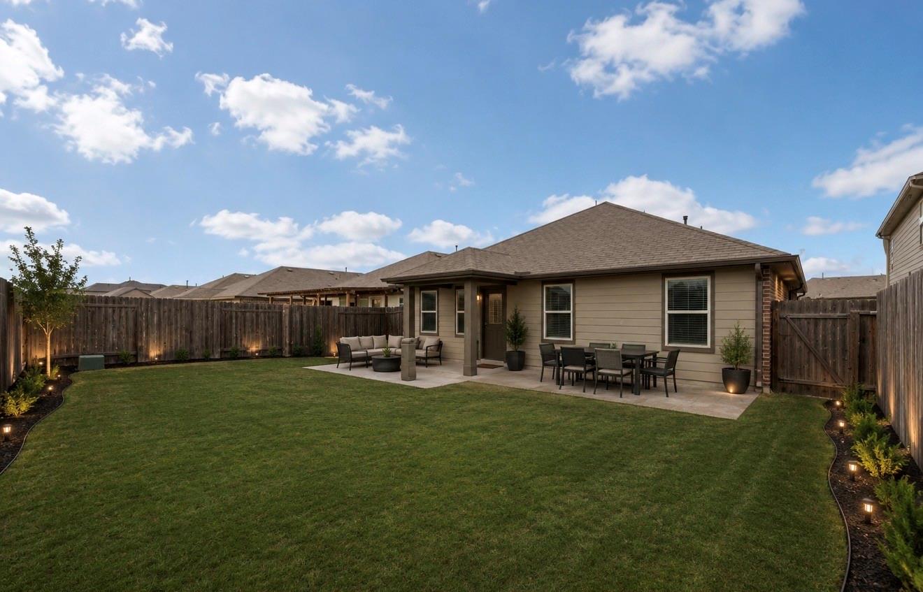 Rear of the home with a fenced lawn, covered patio, and outdoor dining area.