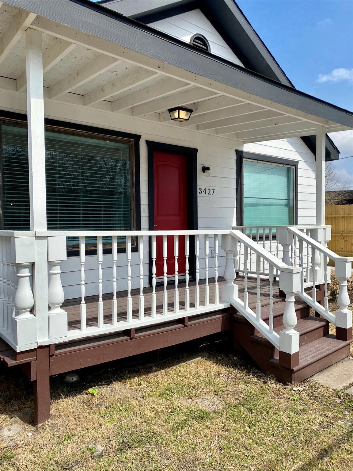 House exterior with a red front door and raised porch with white railings.