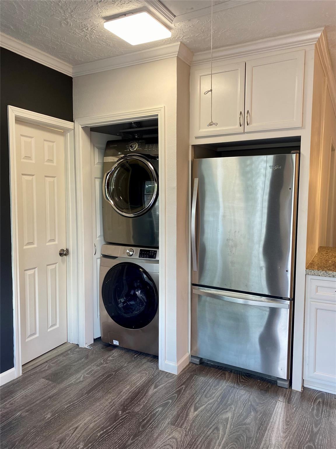 Kitchen with a stainless-steel refrigerator and a closet containing stacked washer and dryer.