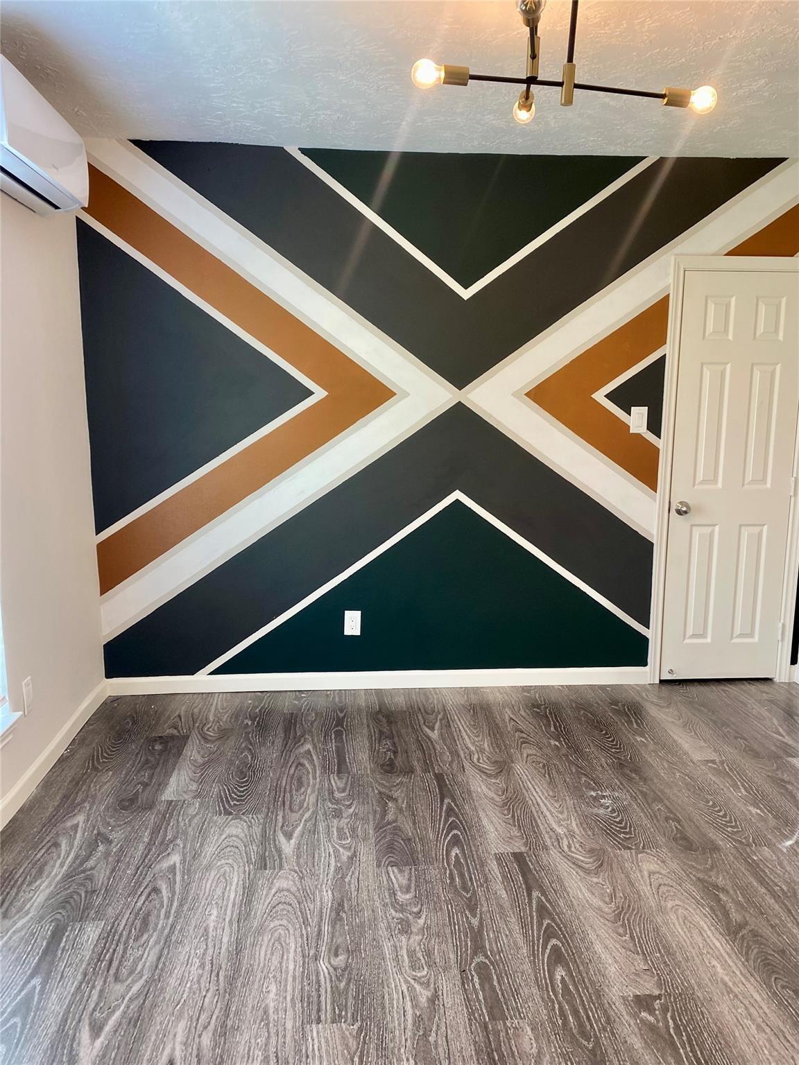 Empty room with a geometric accent wall and gray wood-look flooring.