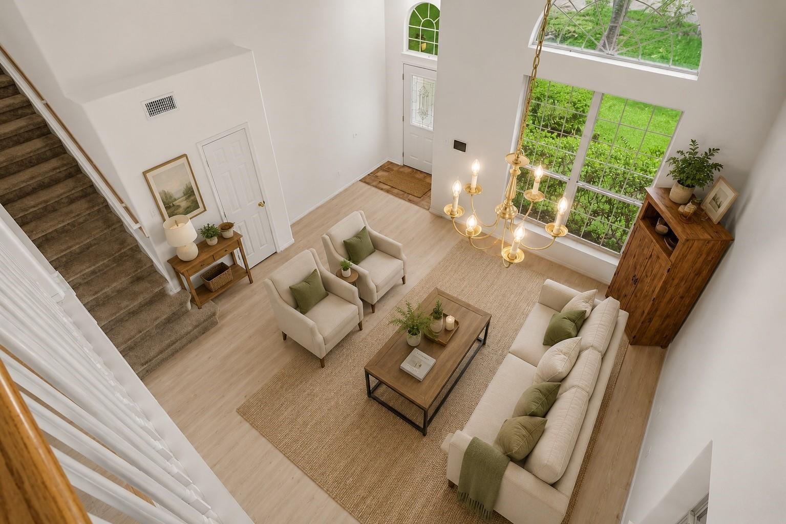 Living room with arched windows, a tall ceiling, carpeted staircase, and chandelier.