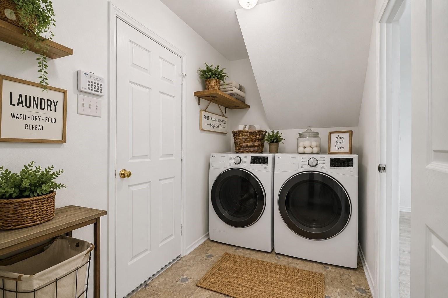 Laundry room with front-loading washer and dryer, wooden shelves, baskets, and framed signs.