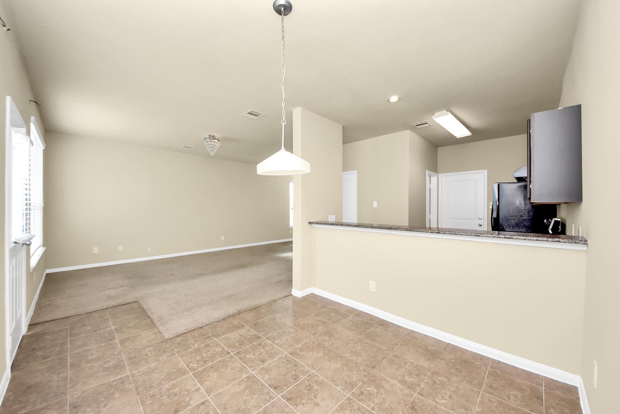 Open dining area with tile flooring and a granite breakfast bar overlooking the kitchen.