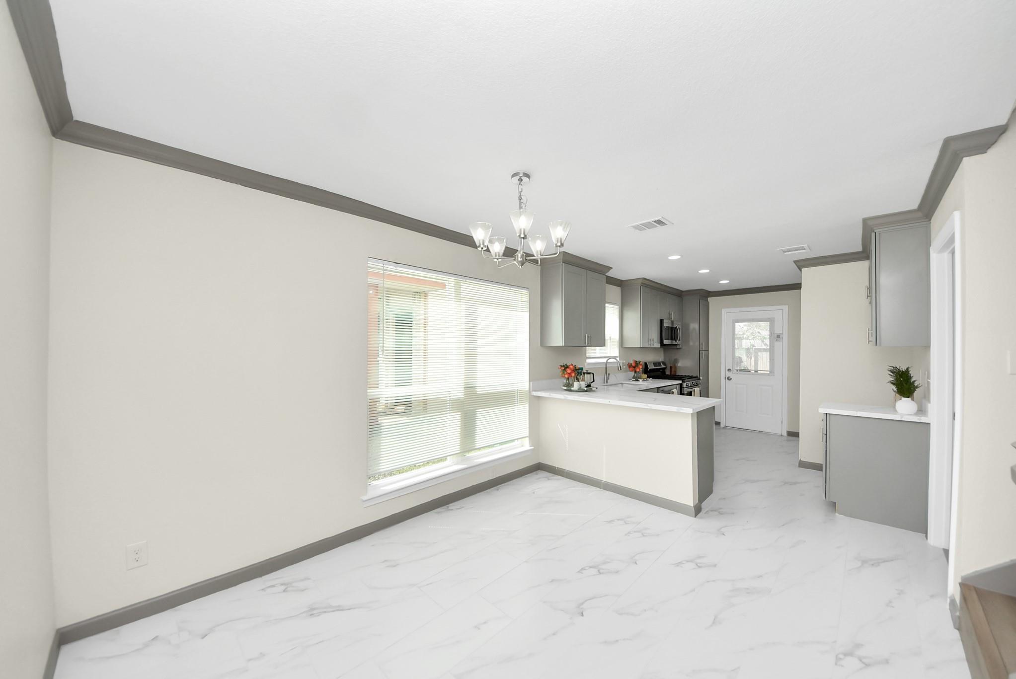 Open dining area and kitchen with gray cabinets, a white peninsula, and marble-look tile floors.